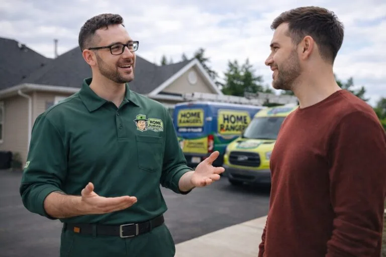 Home rangers technician discussing plumbing service with a homeowner near a service van