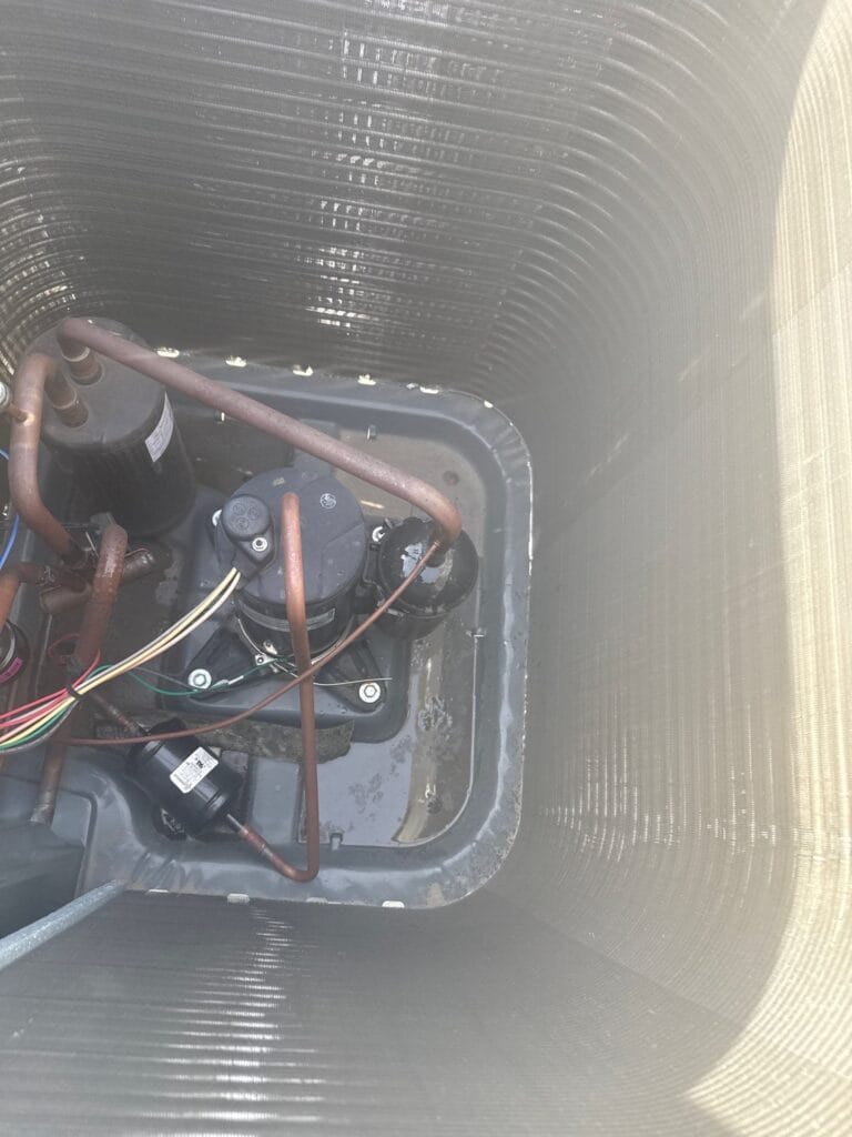 Home rangers technician inspecting ac compressor components inside an outdoor condenser