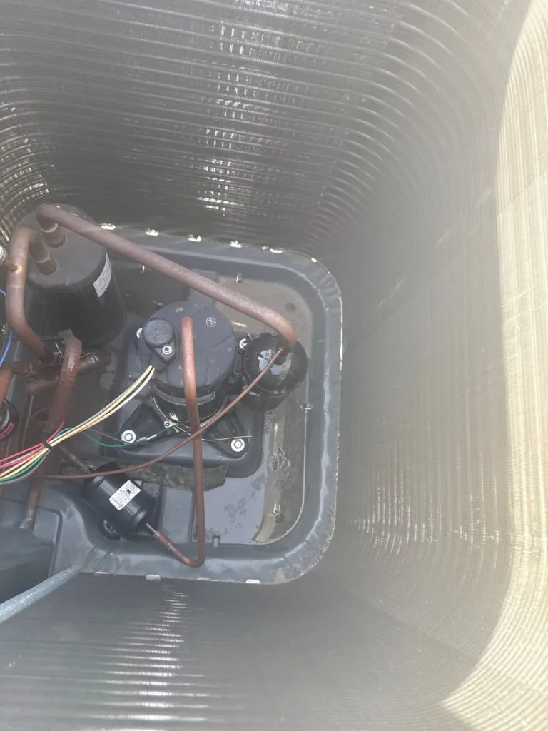 Home rangers technician inspecting ac compressor components inside an outdoor condenser